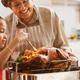 Grandmother and granddaughter smiling and basting turkey